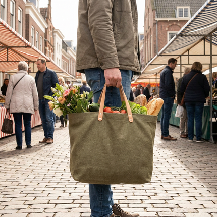 Ruime stijlvolle shopper met stevige handvatten staat vol verse boodschappen op een Europese marktstraat, vastgelegd in zacht natuurlijk daglicht.